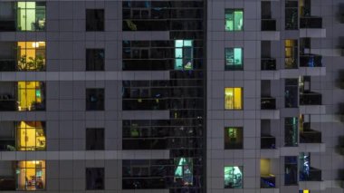 Geceleri apartmanda insanların oturduğu parlak pencereler..