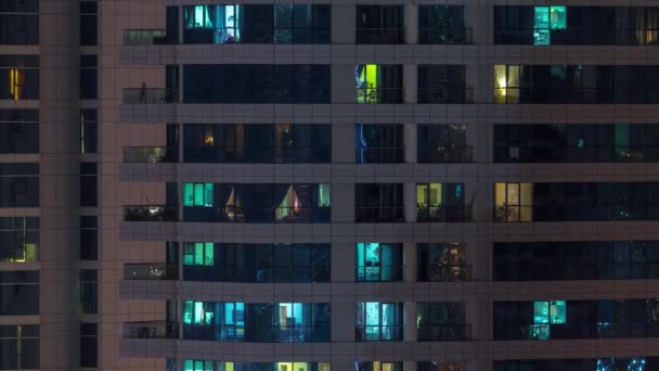 Reihen glühender Fenster mit Menschen in Mehrfamilienhaus in der Nacht. — Stockvideo