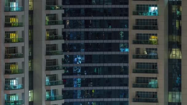 Rijen van gloeiende ramen met mensen in appartementencomplex 's nachts. — Stockvideo