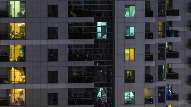 Rækker af glødende vinduer med folk i lejligheden bygning om natten . – Stock-video