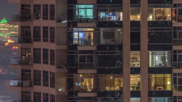 Rows of glowing windows with people in apartment building at night. — Stock Video
