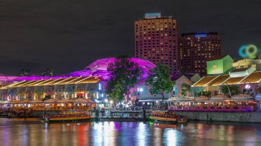 Clarke Quay rıhtımına yanaşan turist tekneleri. Aydınlanmış evlerle dolu bir zaman çizelgesi. Clarke Quay, Singapur 'un Singapur Nehri Planlama Bölgesi' nde bulunan tarihi nehir kenarı rıhtımıdır..