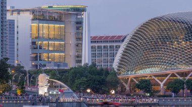 Alacakaranlıkta Singapur Körfezi 'ndeki Esplanade Tiyatrosu' nda. Gündüzden geceye geçiş zamanlarında çok güzel bir yansıması var. Merlion Park 'taki insanlar