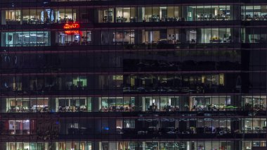 Gece vakti büyük pencereleri olan modern ofis binası yakın çekim manzarası, parlayan pencereler ve Singapur 'daki bazı insanlar. Yakınlaştır