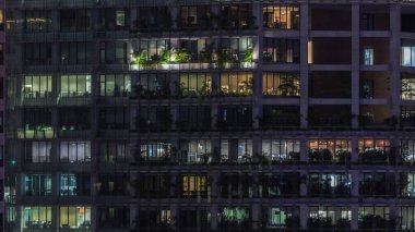 Gece vakti büyük pencereleri olan modern ofis binası yakın çekim manzarası, parlayan pencereler ve Singapur 'daki bazı insanlar. TarayıcıName