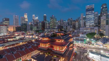 Buddha Diş Kalıntısı Tapınağı, Singapur Çin Mahallesi 'nde gece gündüz canlanır. Arka planda şehrin ufuk çizgisi vardır. Tapınak gökdelenler ve kulelerle aydınlık