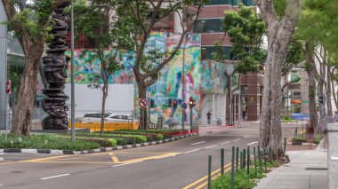 Battery Road Bulvarı 'nda trafik var ve Singapur' un şehir merkezinde yeşil ağaçlarla çevrili. Yeşil çimlerin yanında yürüyen insanlar