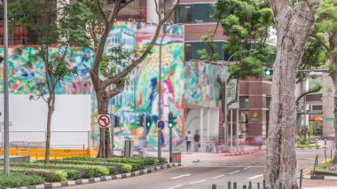 Battery Road Bulvarı 'nda trafik var ve Singapur' un şehir merkezinde yeşil ağaçlarla çevrili. Yeşil çimlerin yanında yürüyen insanlar