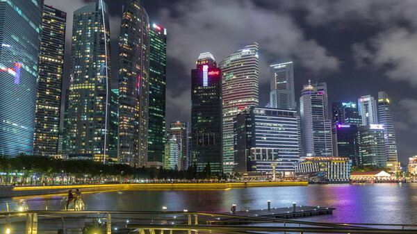 Business Financial Downtown City and Skyscrapers Tower Building at Marina Bay night timelapse hyperlapse, Singapore, Cityscape Urban Landmark and Business Finance District Center reflected in water