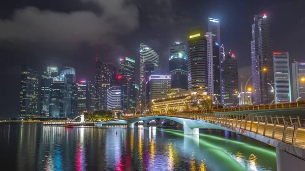 背景にエスプラネード橋とダウンタウンの中心部の超高層ビルシンガポールの夜のタイムラプス 水面に映るライトアップされた塔 — ストック写真