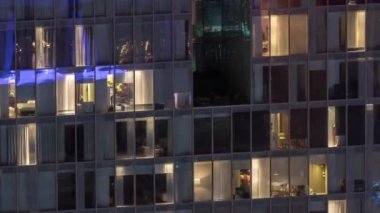 Dış apartman kulesinin gece görüşü. Pencerelerinde yanıp sönen ışıklar olan yüksek gökdelen