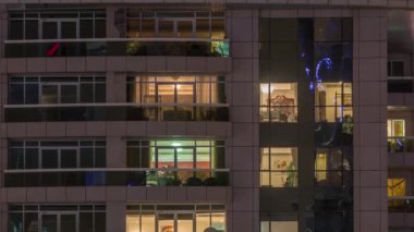 Dış apartman zaman atlamalı gece görünümü. Pencerelerde yanıp sönen ışıklar ile yüksek katlı gökdelen