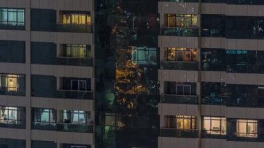 Dış apartman zaman atlamalı gece görünümü. Pencerelerde yanıp sönen ışıklar ile yüksek katlı gökdelen