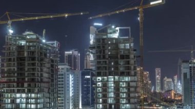 İnşaat halindeki gökdelenlerin hava görüntüsü Dubai 'de gece vakti büyük vinçler var..