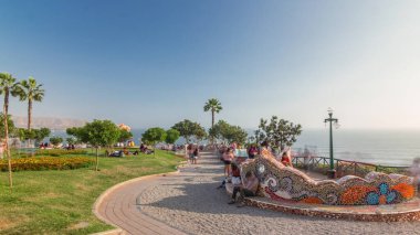 Miraflores, Lima, Peru 'da El Parque del Amor ya da Love Park zaman atlaması. Arka plandaki Kiss heykeli. Mozaik bankta oturan ve etrafta dolaşan insanlar.