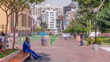Miraflores Central Park ve Kennedy Park zaman çizelgesi. Peru başkentinde yeşil ağaçlar ve çimlerle rahatlamak için bir yer. Banklarda oturan ve yolda yürüyen insanlar. Lima, Peru