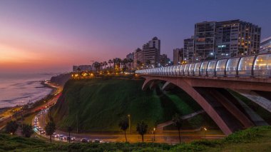 Villena Köprüsü 'nde trafik ve kısmi şehir manzarası var. Günbekten geceye geçiş zamanı, Lima, Peru. Aydınlatılmış kıyı şeridi ve aşk parkı olan hava manzarası