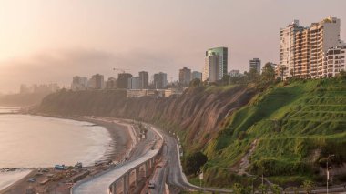Günbatımında Lima 'nın Miraflores civarındaki turuncu ışık, Lima, Peru' daki sahil şeridini gösteren hava manzarası. Husares De Junin rıhtımından okyanusla trafik ve plaj.