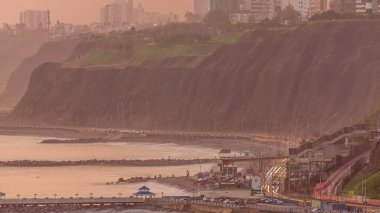 Gün batımında Lima 'nın Miraflores civarındaki Lima' nın Sahil Çizgisi 'nin turuncu ışıkla çekilmiş görüntüsü, Lima, Peru. Trafikli yol ve okyanuslu sahil.
