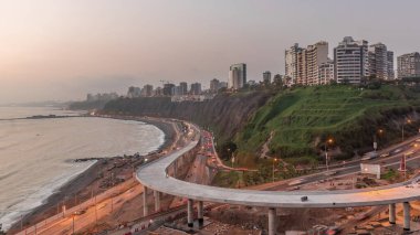Lima 'nın sahil şeridinin havadan panoramik görüntüsü. Miraflores civarındaki gece gündüz geçiş zamanı, Lima, Peru. Husares De Junin rıhtımından okyanusla kesişen yol ve sahil trafiği