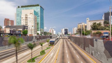 Via Expresa otoyolu ve trafikle dolu metropolitan otobüsün hava manzarası ve bulutlu mavi gökyüzü. Arka planda gökdelenler. Lima, Peru