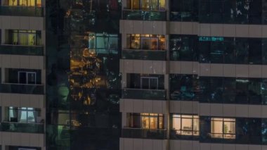 Dış apartman zaman atlamalı gece görünümü. Pencerelerde yanıp sönen ışıklar ile yüksek katlı gökdelen