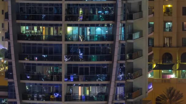 Filas de ventanas brillantes con gente en el edificio de apartamentos por la noche . — Vídeo de stock