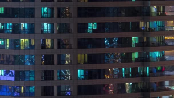 Γραμμές από λαμπερά παράθυρα με τους ανθρώπους στην πολυκατοικία τη νύχτα. — Αρχείο Βίντεο