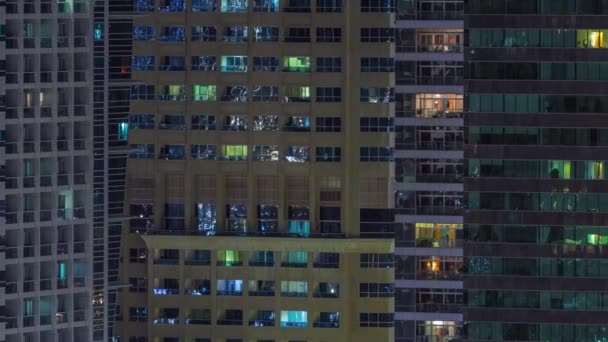 Řady zářících oken s lidmi v činžovním domě v noci. — Stock video