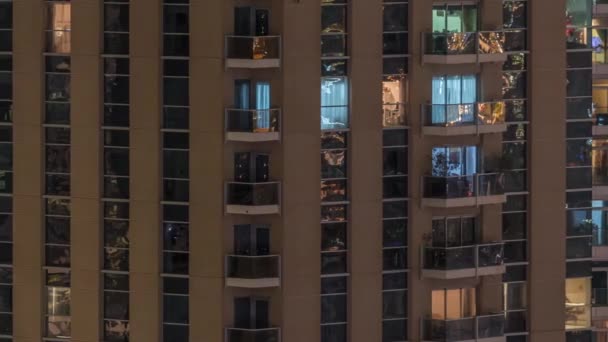 Γραμμές από λαμπερά παράθυρα με τους ανθρώπους στην πολυκατοικία τη νύχτα. — Αρχείο Βίντεο