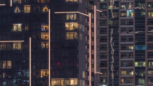 Rows of glowing windows with people in apartment building at night. — Stock Video