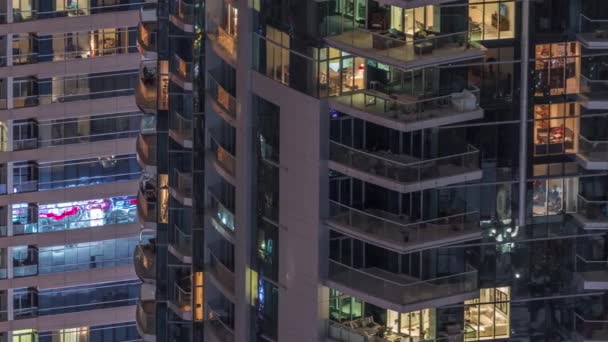 Filas de ventanas brillantes con gente en el edificio de apartamentos por la noche . — Vídeos de Stock