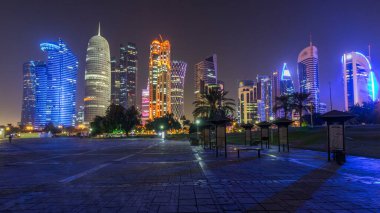 Doha 'nın yüksek katlı bölgesinde gece vardiyası, parktan görülmüş. Batı körfezinde aydınlatılmış gökdelenler ve palmiyeler