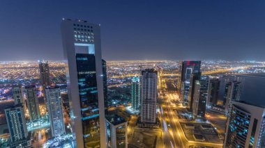 Katar 'ın Doha Zaman Çizelgesi' nde Batı Körfezi bölgesinin ufuk çizgisi. Aydınlatılmış modern gökdelenler geceleri çatıdan gökyüzü manzarası