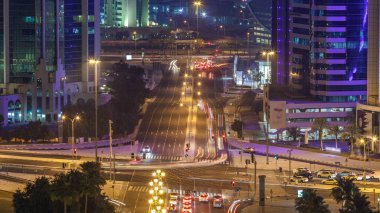Katar, Doha Timelapse 'da West Bay yolunda trafik var. Aydınlatılmış modern gökdelenler ve gece çatıdan kesişen hava manzarası.