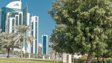 Batı Körfezi 'ndeki Doha' s Corniche 'de modern gökdelenler ve ağaçlarla, Katar. Corniche, fantastik gezinti yerleri, su sporları, geleneksel dhow yarışları ve daha pek çok şeyle bilinen popüler bir egzersiz mekanıdır.