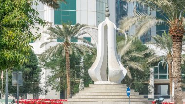 Doha Corniche kahve demliği anıtlı zaman dilimi. Arka planda modern gökdelenler ve yanlarda palmiyeler