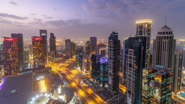 Batı Körfezi bölgesinin ufuk çizgisi Doha 'da günden geceye geçiş zamanı, Katar. Günbatımından sonra modern gökdelenlerin çatıdan görünüşü aydınlandı. Yolda trafik vardı.