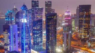 Skyline of the West Bay area from top in Doha day to night transition timelapse, Qatar. Illuminated modern skyscrapers aerial view from rooftop at evening after sunset. Traffic on the road clipart