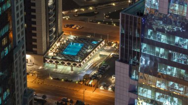 Katar 'ın Doha Timelapse bölgesinin batı yakası. Aydınlatılmış modern gökdelenler ve geceleri çatıdan havuz manzarası. Yolda trafik vardı.