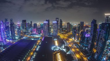 Katar 'ın Doha Zaman Çizelgesi' nde Batı Körfezi bölgesinin ufuk çizgisi. Aydınlatılmış modern gökdelenler geceleri çatıdan gökyüzü manzarası. Yollarda trafik vardı. Fisheye merceği