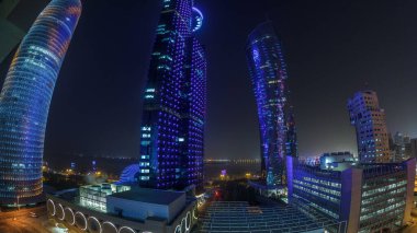 Katar 'ın Doha Zaman Çizelgesi' nde Batı Körfezi bölgesinin ufuk çizgisi. Aydınlatılmış modern gökdelenler geceleri çatıdan gökyüzü manzarası. Arka plandaki körfez ve yoldaki trafik