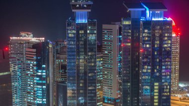 Katar 'ın Doha Zaman Çizelgesi' nde Batı Körfezi bölgesinin ufuk çizgisi. Aydınlatılmış modern gökdelenler geceleri çatıdan gökyüzü manzarası. Yolda trafik vardı.