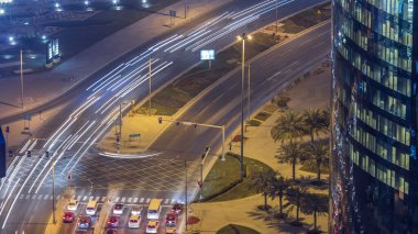 Katar, Doha Timelapse 'da West Bay yolunda trafik var. Aydınlatılmış modern gökdelenler ve gece çatıdan kesişen hava manzarası.