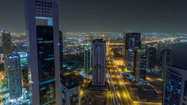 Katar 'ın Doha Zaman Çizelgesi' nde Batı Körfezi bölgesinin ufuk çizgisi. Aydınlatılmış modern gökdelenler geceleri çatıdan gökyüzü manzarası. Yolda trafik vardı.