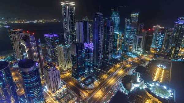 Katar 'ın Doha Zaman Çizelgesi' nde Batı Körfezi bölgesinin ufuk çizgisi. Aydınlatılmış modern gökdelenler geceleri çatıdan gökyüzü manzarası. Yolda trafik vardı.