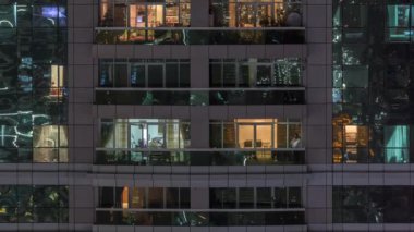 Dış apartman zaman atlamalı gece görünümü. Pencerelerde yanıp sönen ışıklar ile yüksek katlı gökdelen