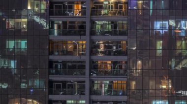 Dış apartman zaman atlamalı gece görünümü. Pencerelerde yanıp sönen ışıklar ile yüksek katlı gökdelen