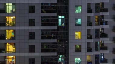 Geceleri apartmanda insanların oturduğu parlak pencereler..