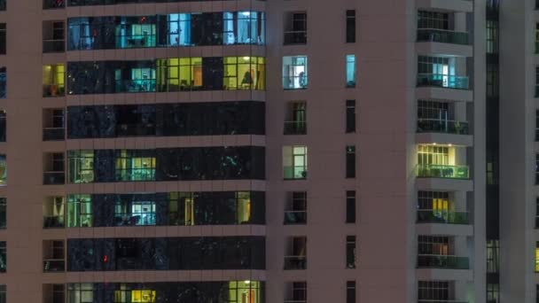 밤에 아파트 건물에 있는 사람들 과 함께 빛나는 창문들이 줄지어서 있다. — 비디오